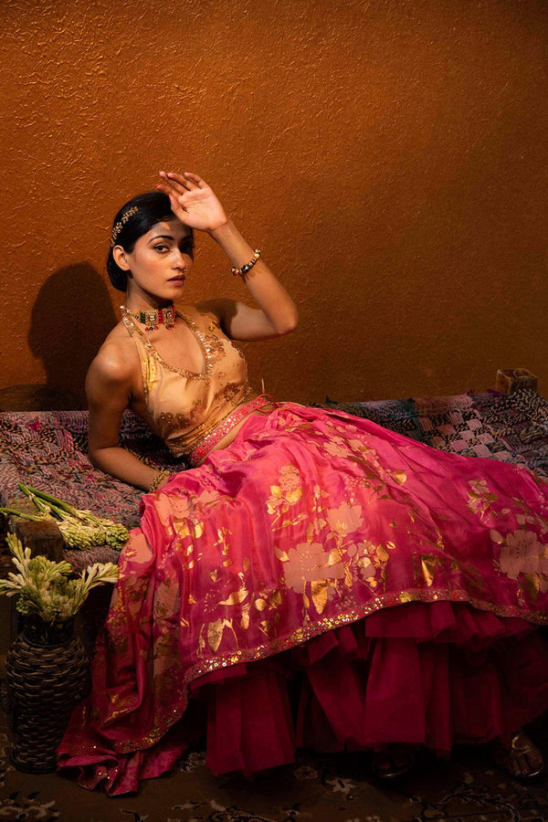 Flared fuchsia lehenga with creased texture and shimmering gold foil highlights.